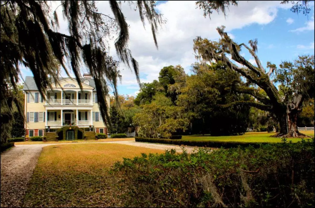 Large white two-story plantation house framed by live oaks on Edisto Island, a private historic home