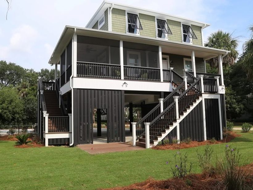 Green-and-black raised rental home with a large lawn on Edisto Island