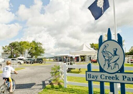 Triathlon cyclist riding past the Bay Creek Park sign on Edisto
