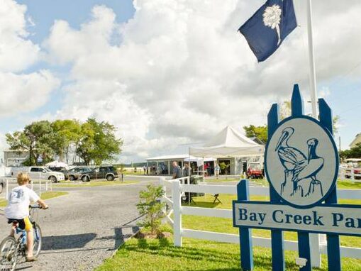 Triathlon cyclist riding past the Bay Creek Park sign on Edisto